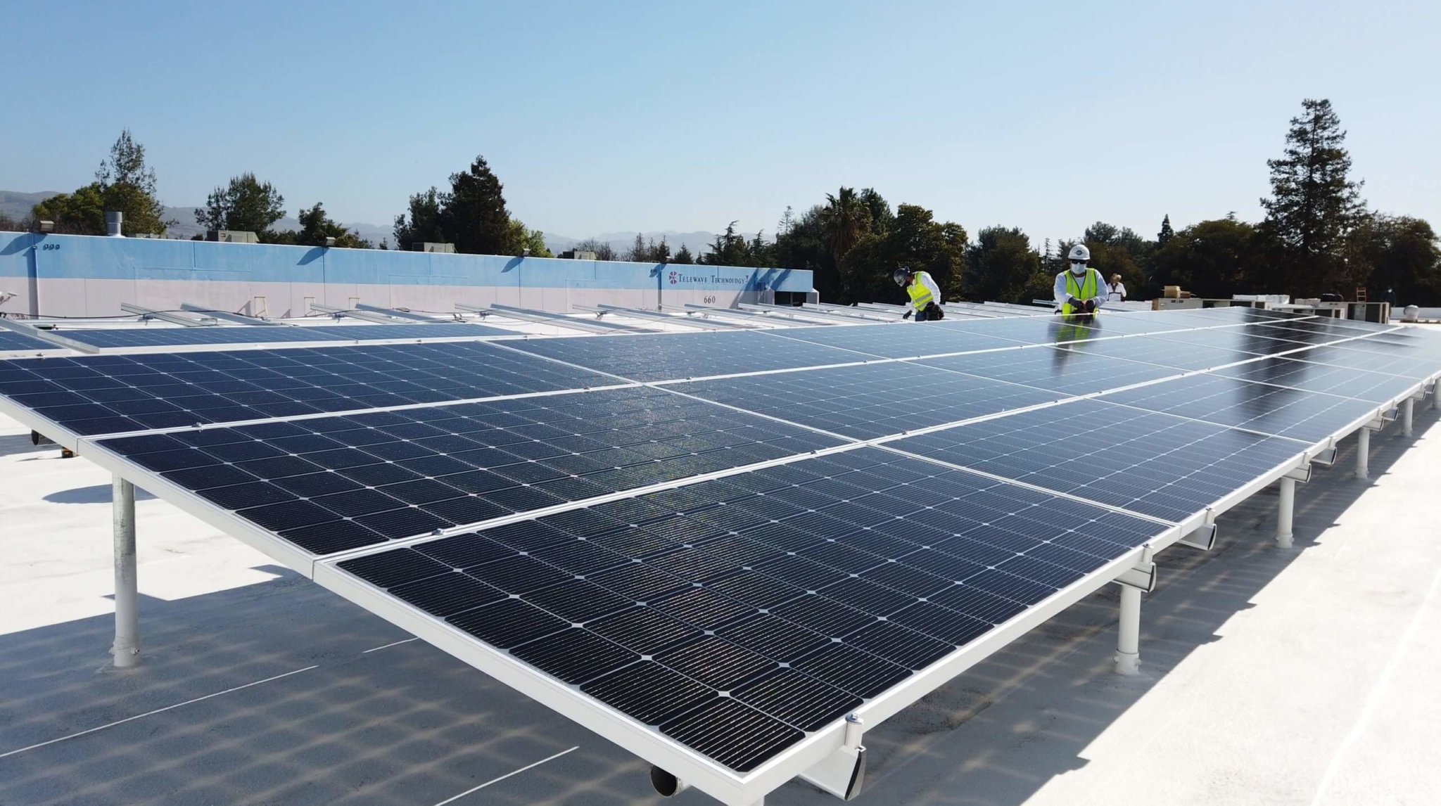 Technicians installing solar panels on a commercial roof